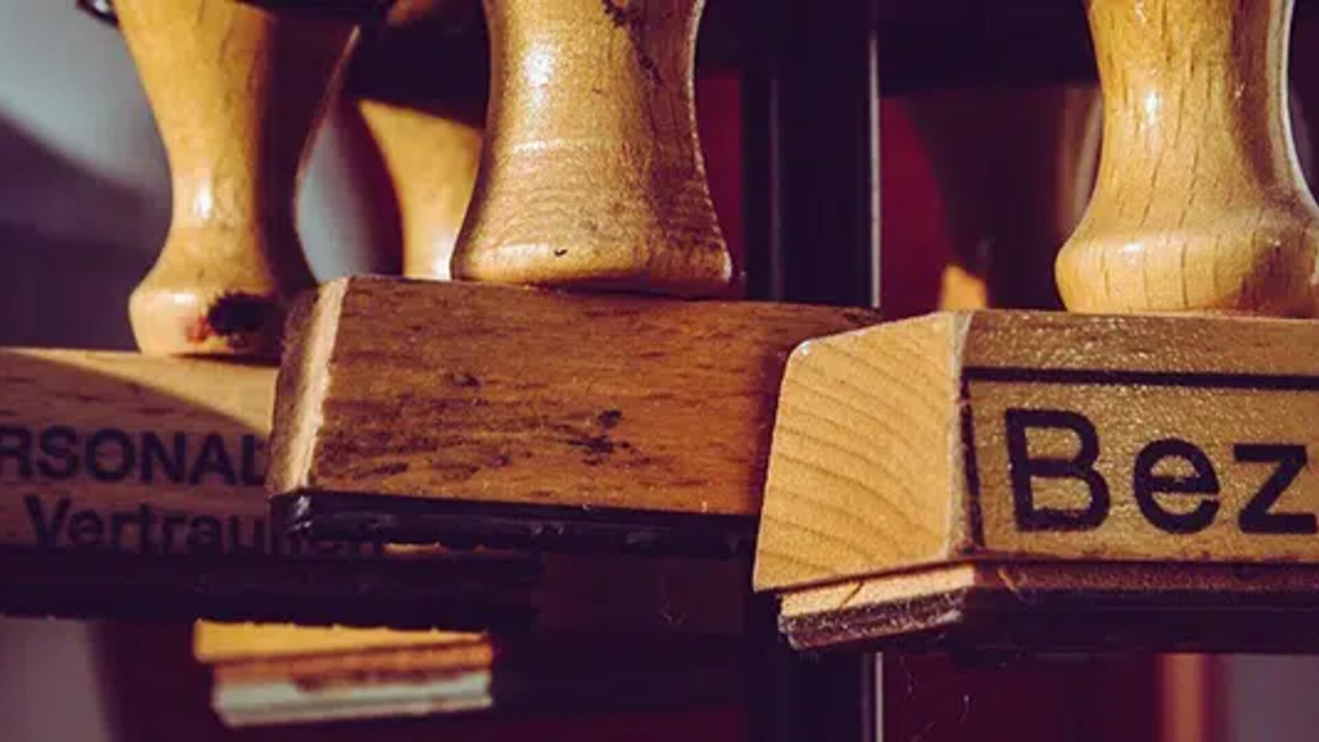 Close-up of wooden stamps, one of which is labeled 'Bezahlt' (Paid in German), symbolizing completed financial transactions